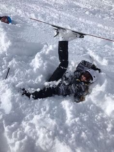 a person laying in the snow with skis on their head