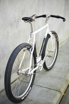 a white and black bike leaning against a wall