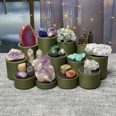 there are many rocks and crystals in the tins on the table with lights behind them