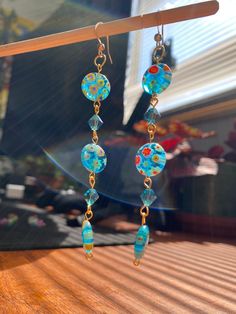 These Blue Millifiori Glass beaded earrings are handmade. Blue swarovski crystals between gold coated brass wire. Perfect for summer beach days. These earrings have a sprinkle of fairycore and cottagecore aesthetics, boho or hippie style and upcycled useing passed down and thrifted material.  Great gift for her, a friend, or yourself!  Drop length: 3.2 in Free shipping on all my products 🍊🧡and a 21 day return and exchange policy. Don't hesitate to reach out to me for any questions! Blue Wire Wrapped Dangle Crystal Earrings, Blue Bohemian Wire Wrapped Crystal Earrings, Bohemian Blue Wire Wrapped Crystal Earrings, Blue Czech Glass Beaded Earrings Wire Wrapped, Blue Czech Glass Wire Wrapped Beaded Earrings, Handmade Blue Bohemian Crystal Earrings, Earrings Handmade Boho, Bead Dangle Earrings, Summer Earrings