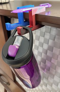 a purple and blue water bottle hanging from a hook