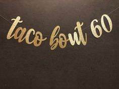 a taco bout 30 banner hanging from a string on a black wall with the word taco bout 30 spelled in gold foil