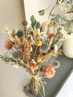 an arrangement of wildflowers in a vase on a table next to a mirror