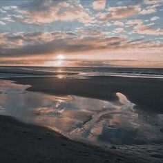 the sun is setting over an empty beach