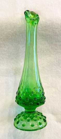 a green glass vase sitting on top of a white table