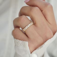 a woman's hand wearing a gold ring with three stones on it and a diamond band