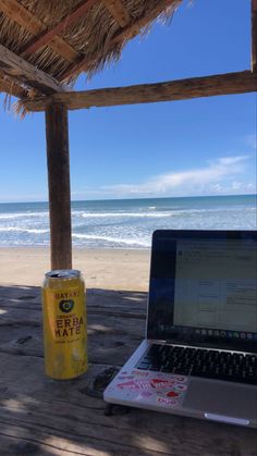 an open laptop computer sitting on top of a wooden table next to a can of soda