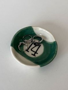 a small green and white bowl with a pair of scissors in the shape of a horse