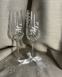 two wine glasses sitting next to each other on top of a cloth covered tablecloth