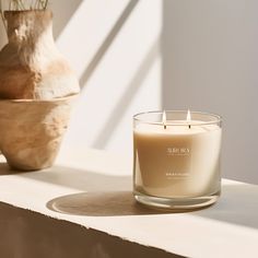 a candle sitting on top of a table next to a vase and potted plant