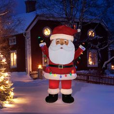 a large inflatable santa clause standing next to a christmas tree and lit up lights