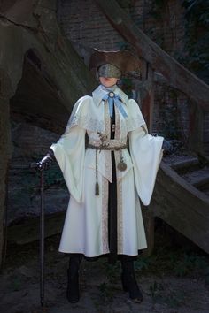 a man dressed in medieval clothing standing next to a wooden structure with stairs behind him