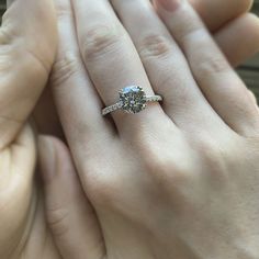 a close up of a person holding an engagement ring in their hand with the other hand