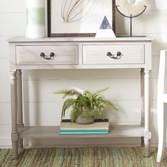 a white table with two drawers and a potted plant sitting on top of it