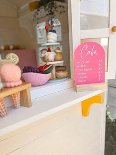 an ice cream shop with cakes and other desserts on display in the window sill