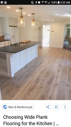 an empty kitchen with white cabinets and wood floors