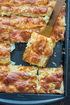 a pan filled with food and a wooden spatula on top of the baking dish