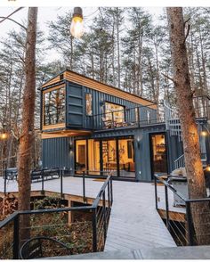 a small house made out of shipping containers in the woods with stairs leading up to it