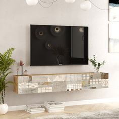 a tv mounted to the side of a white wall next to a potted plant