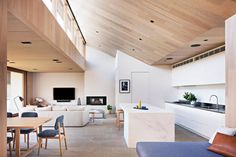 a living room filled with furniture and a flat screen tv mounted to a wall next to a kitchen