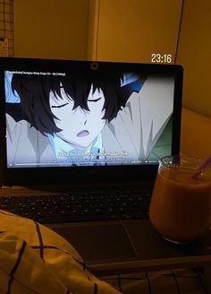 an open laptop computer sitting on top of a bed next to a glass of milk