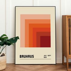 a poster with the name bauhus on it next to a potted plant