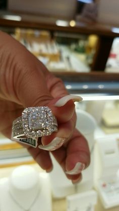 a close up of a person's hand holding a ring with diamonds on it