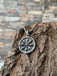 a compass pendant on a tree trunk