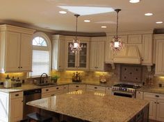 a large kitchen with white cabinets and granite counter tops, an island in the middle