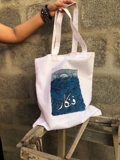 This tote features originality in design, concept and thought. Embrace the Artistic Fusion: Fankar (فنکار) Hand-Painted Tote - Where Cultures Converge. This stunning masterpiece transcends language barriers, blending the allure of Urdu calligraphy with the universal language of art. With each brushstroke, Fankar comes to life, imbuing the fabric with the rich essence of creative expression. This hand-painted tote is not only a cherished possession for artists; it is a symbol of unity and appreci Urdu Art, Truck Art Pakistan, Pakistani Art, Painted Tote, Truck Art, Art Bag, Hand Painted Canvas, Creative Expressions, Custom Tote