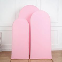 two pink chairs sitting next to each other in front of a white wall