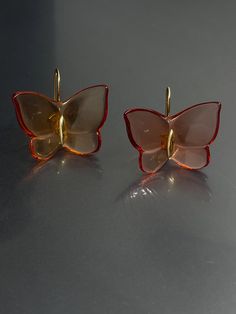 Elevate your style with these stunning Baccarat earrings. Crafted with yellow gold and amber tone crystal/glass, these earrings feature a beautiful butterfly design with a hook closure for easy wear. The dangle/drop style adds a touch of elegance to any outfit and the 1" length is perfect for the lobe area. These earrings are signed by Baccarat and boast a unique combination of beauty, nature, art, animals & insects, bohemian, and fashion & costumes themes. The crystal/glass material adds a spar Luxury Gold Butterfly Earrings, Gold Butterfly Earrings For Formal Occasions, Luxury Yellow Gold Butterfly Earrings, Gold Earrings With Butterfly Charm For Formal Events, Gold Earrings With Butterfly Charm For Formal Occasion, Luxury Amber Drop Earrings, Luxury Clear Earrings For Formal Events, Orange Clip-on Earrings For Formal Occasions, Formal Orange Clip-on Earrings