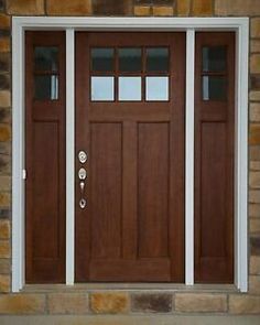 the front door is made of wood and has two sidelights on each side, along with white trim