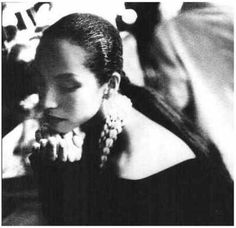 a black and white photo of a woman with large earrings on her head looking down