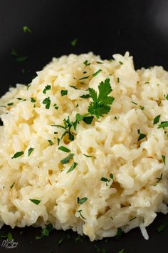 mashed potatoes with parsley on top in a black bowl, ready to be eaten