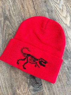 Welcome to my shop! If you know a child that loves dinosaurs this beanie is for you! Its embroidered with high quality thread and can be customized! It has a T-Rex embroidered right on the front of the hat! Its a one size fits most! If you have any questions please send me a message! Thank you for stopping by! Novelty Cap Beanie One Size Fits Most, Novelty One Size Fits Most Cap Beanie, Novelty One-size-fits-most Beanie Cap, Warm Novelty Beanie, One Size Fits Most, Novelty Warm Beanie, One Size Fits Most, Novelty Warm Beanie One Size Fits Most, Warm Novelty Beanie One Size Fits Most, Gift Beanie One Size Fits Most, Adjustable Novelty Beanie Cap