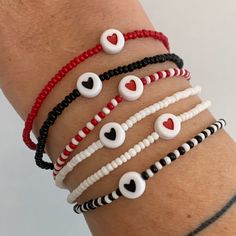 four bracelets with white and red beads on each arm, one has an eyeball in the middle