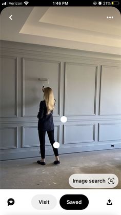 a woman standing in an empty room with her back to the camera and looking at something