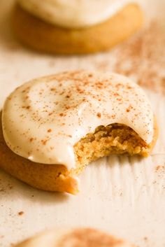 two cookies with white frosting and cinnamon sprinkles are on the table