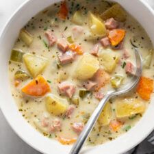 a bowl of ham and potato soup with a spoon