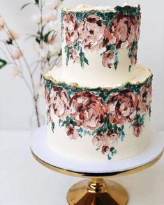 a three tiered cake with flowers painted on the side and gold trimmings