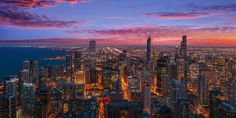 an aerial view of the chicago skyline at night with lights on and skyscrapers lit up