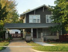 a gray house with trees and grass in the front yard