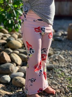 a woman standing on rocks with her hands in her pockets and wearing pink floral pants