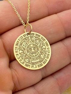 "14k Aztec Calendar Necklace, Personalized Mayan Sun Calendar Pendant, Aztec Coin Pendant, Sun Stone Aztec Calendar Necklace 14k Solid Gold Choose What Size You Want the Pendant Using The First Option Box Choose Chain Length Or Without Chain Using The Second Option Box Photos Are For The 25.4 mm / 1 Inch Diameter Pendant Pendant thickness : 0.7mm  Contact us if you want it thicker Inner diameter of jump ring : 5mm Contact us if you need it bigger  Chain width : 1.30mm     ♥  Material of pendant and chain: Solid Gold k14  ♥  Packaging: All of our jewelry are beautifully boxed and ready for gifting For more personalized designs take a look here: ♥ www.etsy.com/listing/736955132 ♥ www.etsy.com/listing/819494857 ♥ www.etsy.com/listing/823397880 ♥ www.etsy.com/listing/769847320 ♥ www.etsy.com/l Symbolic Brass Jewelry With Coin Pendant, Symbolic Gold Plated Coin Jewelry, Symbolic Gold-plated Round Pendant, Sterling Silver Etched Coin Jewelry, Symbolic Gold Plated Round Pendant Jewelry, 14k Gold Amulet Jewelry With Coin Pendant, Engraved 14k Gold Amulet Coin Necklace, Coin-shaped Amulet Jewelry For Gifts, Coin-shaped Amulet Jewelry Gift