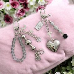 a bunch of charms are laying on a pink blanket next to flowers and other items