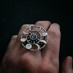 "What a knockout! This textured gold or silver tone ring is set with the Earth in glass surrounded by 8 different phases of the moon in a round halo. Celebrate the cosmos and our planetary home with this piece of galaxy jewelry! Ring Size: Adjustable Design Size: 1 1/4\" (3.2cm) Materials: brass, glass ★ These are individually handcrafted and the particular piece you receive may vary slightly from what is pictured. These are also not 100% waterproof, so please avoid submerging them in water. ★ D Spiritual Open Ring Jewelry With Moon Phase, Spiritual Moon Phase Open Ring Jewelry, Adjustable Moon Shaped Celestial Rings, Adjustable Moon-shaped Celestial Rings, Celestial Silver Ring With Moon Charm, Celestial Crystal Ring In Sterling Silver, Celestial Sterling Silver Crystal Ring, Sterling Silver Celestial Crystal Ring, Silver Moon Phase Crystal Ring