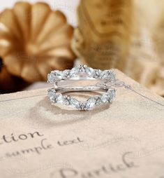 two wedding rings sitting on top of a piece of paper next to a vase with flowers