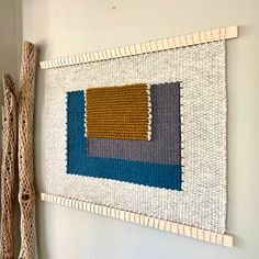 a wall hanging made out of woven material with two wooden sticks attached to the wall