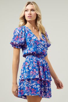 Bubbly florals to brighten your day. Keep things fresh and fun in the Junie Floral Amina Dress. Ruffle puff sleeves frame a surplice neckline where it meets a smocked waist. Ruffle layers add a flirty flair to the mini skirt. Wear it with slingbacks and a wide brim hat.- Surplice- Smocked waist- Lined- Ruffle layer- Color: Blue PinkSize + Fit - Model is 5'10" and wearing size XS- Measurements taken from size S - Chest: 9 3/4"- Length: 34" Fabric Self: 100% Polyester Lining: 97% Polyester 3% Span Blue V-neck Floral Dress With Ditsy Print, Blue Floral V-neck Dress For Spring, Blue V-neck Floral Dress For Spring, Surplice Neckline, Ruffle Mini Dress, Slingbacks, Wide Brimmed Hats, Brim Hat, Wide Brimmed